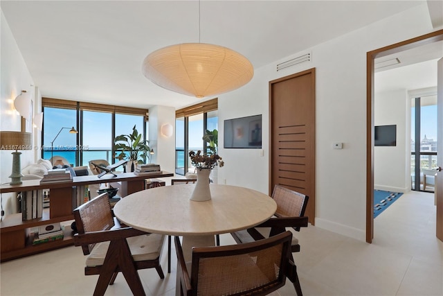 dining room with expansive windows, a healthy amount of sunlight, and a water view