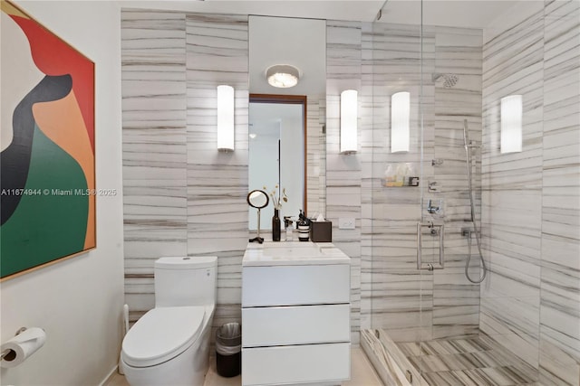 bathroom featuring vanity, a shower with shower door, tile walls, and toilet