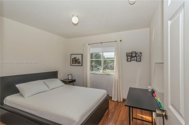 bedroom featuring a textured ceiling and dark wood-type flooring