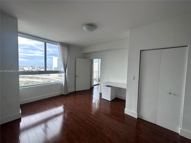 unfurnished bedroom with dark wood-type flooring and built in desk