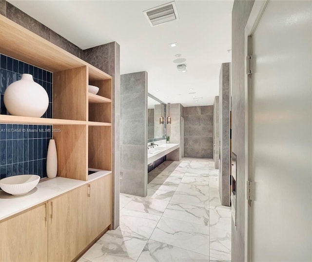 bathroom featuring a bath, vanity, and tile walls