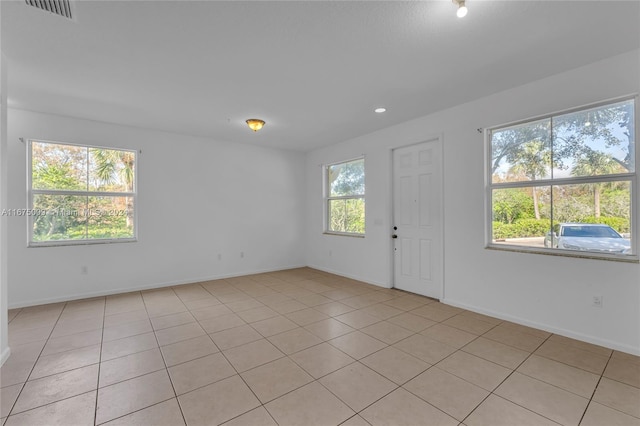 empty room featuring a healthy amount of sunlight and light tile patterned flooring