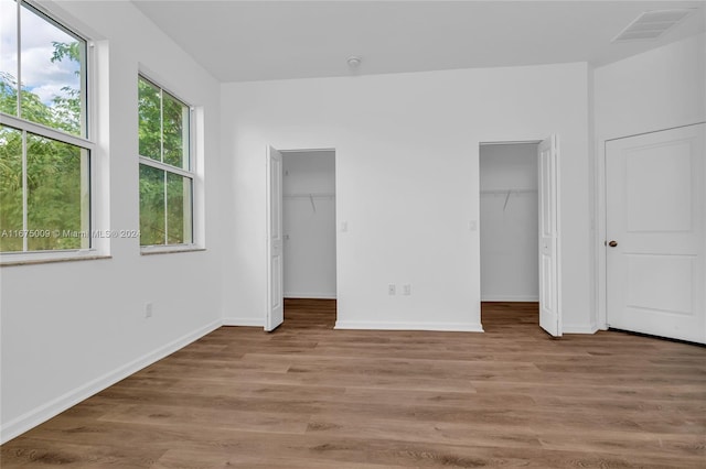 unfurnished bedroom featuring a spacious closet and light hardwood / wood-style flooring