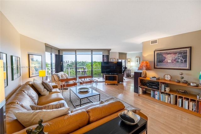 living room with light hardwood / wood-style floors and a wall of windows