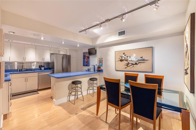 kitchen with sink, a breakfast bar area, tasteful backsplash, kitchen peninsula, and stainless steel appliances