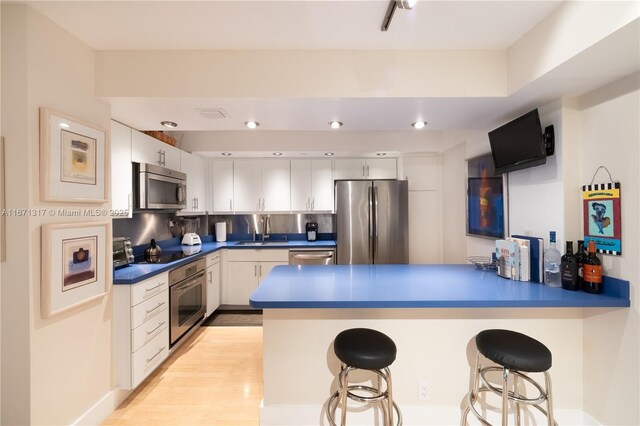 kitchen featuring decorative backsplash, sink, white cabinets, and stainless steel appliances