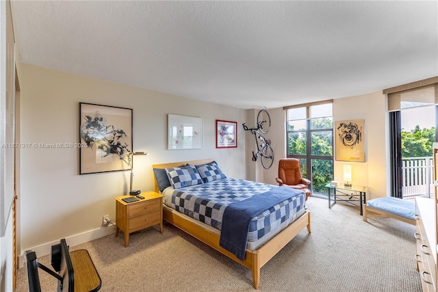 carpeted bedroom featuring access to exterior, a textured ceiling, and a wall of windows