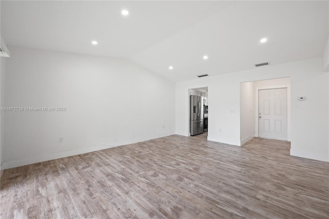 unfurnished room featuring lofted ceiling and light wood-type flooring