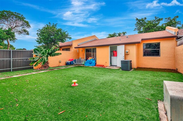 rear view of house featuring a yard and central AC unit