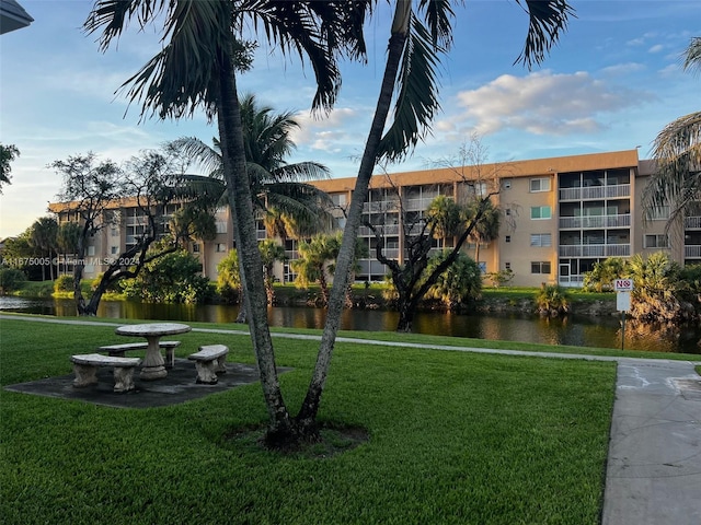 view of property's community featuring a lawn and a water view