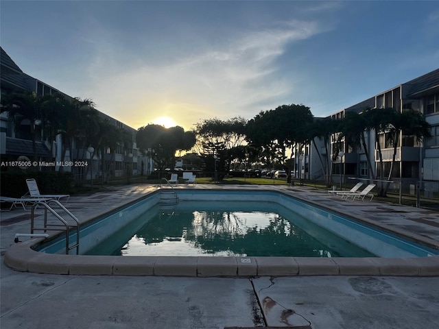 pool at dusk featuring a patio area