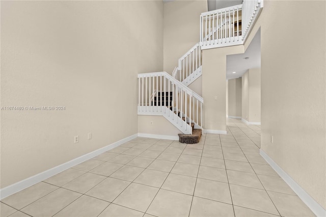 staircase with a towering ceiling and tile patterned floors