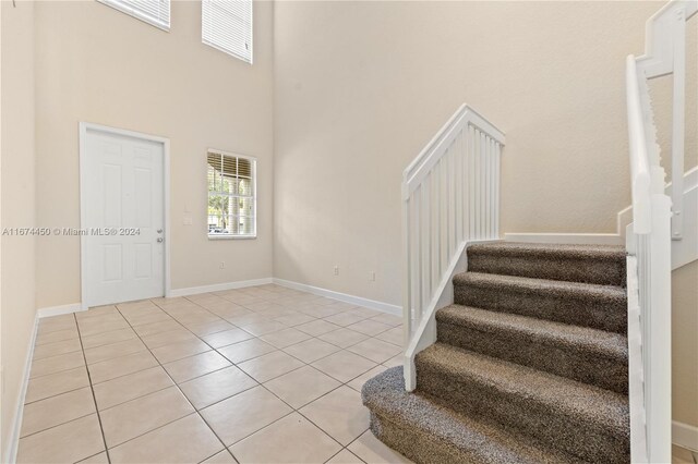 stairs with tile patterned flooring and a high ceiling