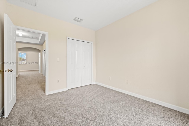 unfurnished bedroom featuring a closet and light carpet