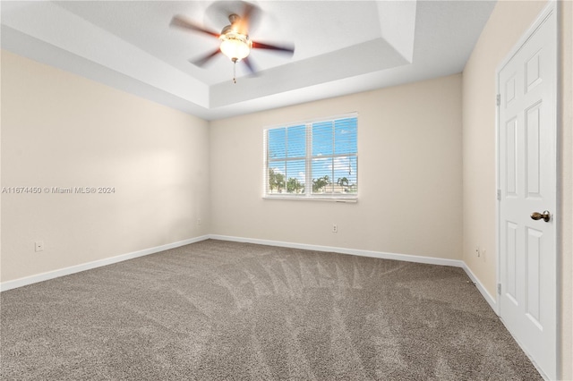 unfurnished bedroom featuring ceiling fan, a tray ceiling, and carpet flooring