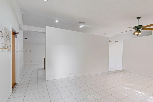 spare room featuring a textured ceiling, ceiling fan, light tile patterned flooring, and vaulted ceiling