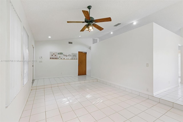 tiled spare room with ceiling fan, lofted ceiling, and a textured ceiling