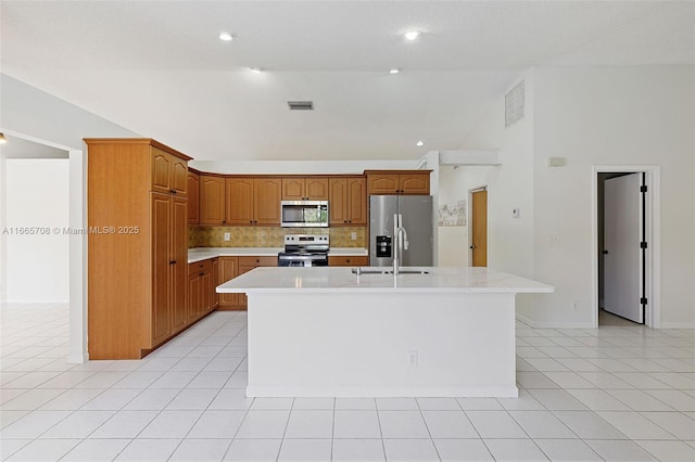 kitchen with sink, a center island with sink, light tile patterned floors, and appliances with stainless steel finishes