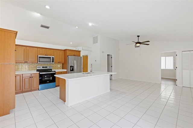 kitchen featuring lofted ceiling, backsplash, a center island with sink, sink, and appliances with stainless steel finishes