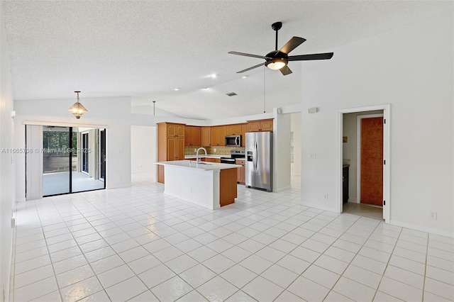 kitchen with stainless steel appliances, vaulted ceiling, ceiling fan, pendant lighting, and an island with sink