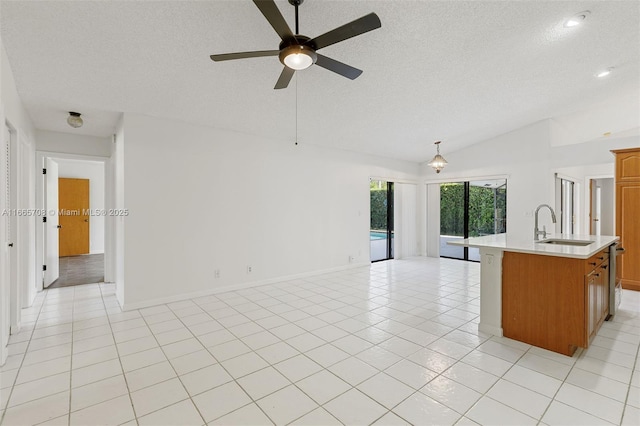 kitchen with pendant lighting, lofted ceiling, a center island with sink, sink, and ceiling fan