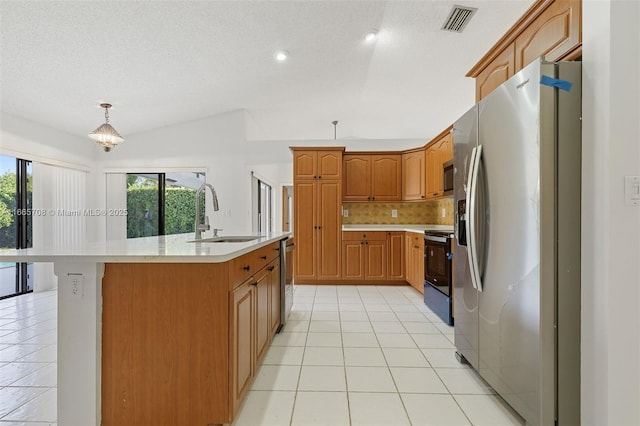 kitchen featuring pendant lighting, backsplash, a kitchen island with sink, sink, and stainless steel appliances