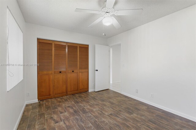 empty room featuring dark hardwood / wood-style floors, ceiling fan, and a textured ceiling