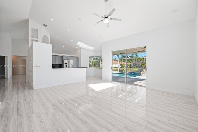 unfurnished living room with high vaulted ceiling and ceiling fan