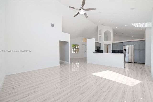 unfurnished living room with high vaulted ceiling and ceiling fan