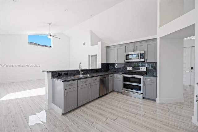 kitchen featuring gray cabinetry, sink, dark stone countertops, appliances with stainless steel finishes, and kitchen peninsula