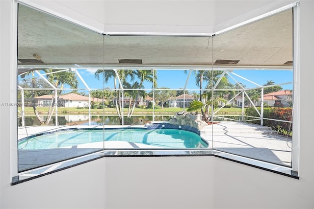 view of pool with glass enclosure, a water view, and a patio