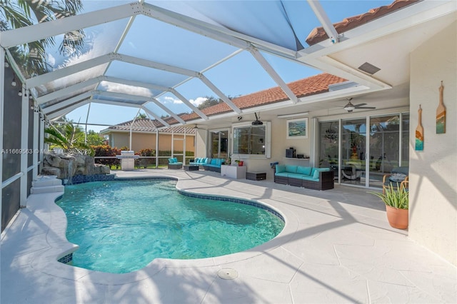 view of pool with outdoor lounge area, pool water feature, ceiling fan, glass enclosure, and a patio