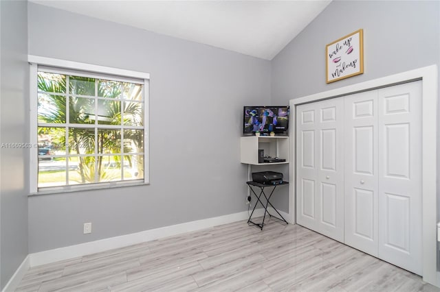 bedroom featuring a closet, light hardwood / wood-style flooring, multiple windows, and lofted ceiling