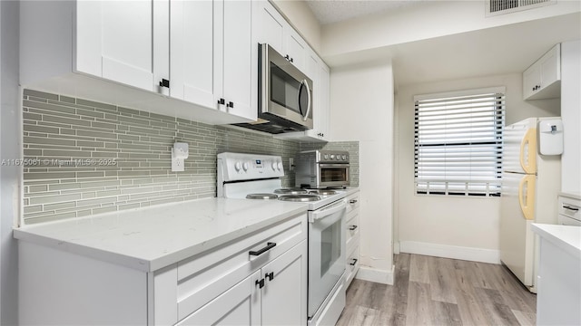 kitchen with light hardwood / wood-style flooring, tasteful backsplash, white cabinetry, light stone counters, and white appliances