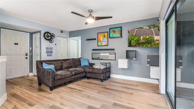 living room featuring ceiling fan, a textured ceiling, and light wood-type flooring