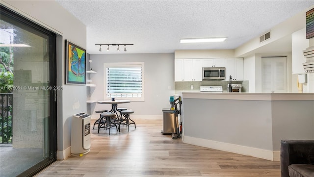 kitchen with sink, backsplash, white cabinets, a textured ceiling, and light hardwood / wood-style floors