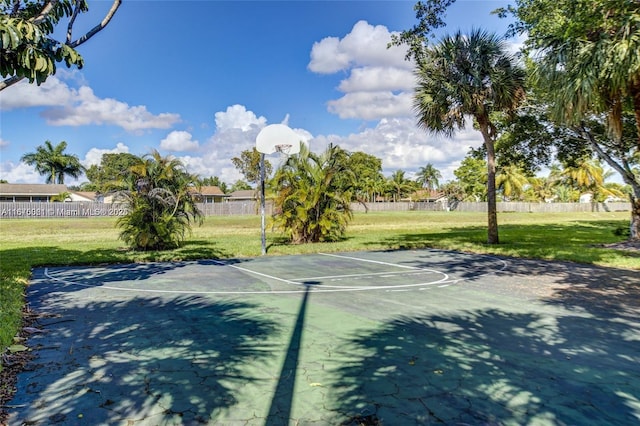 view of tennis court with community basketball court, fence, and a lawn