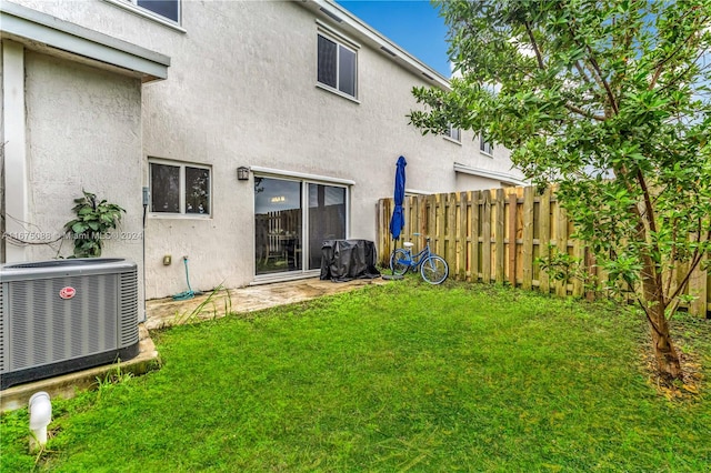 back of house featuring central air condition unit and a yard