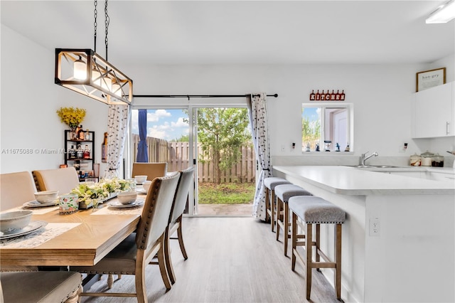 dining space with a chandelier, sink, and light wood-type flooring