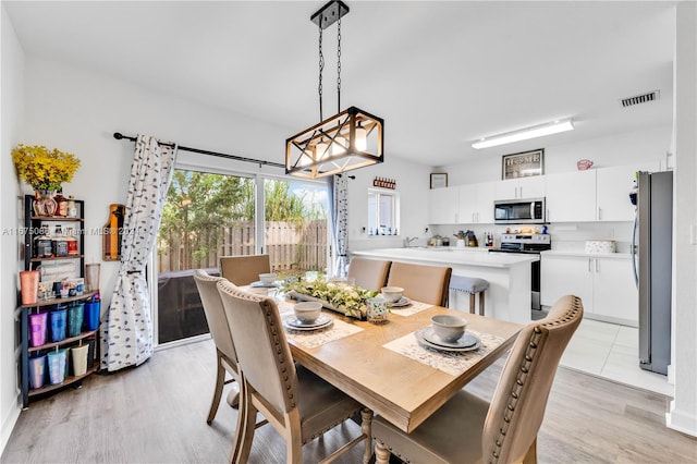 dining space featuring an inviting chandelier, sink, and light wood-type flooring