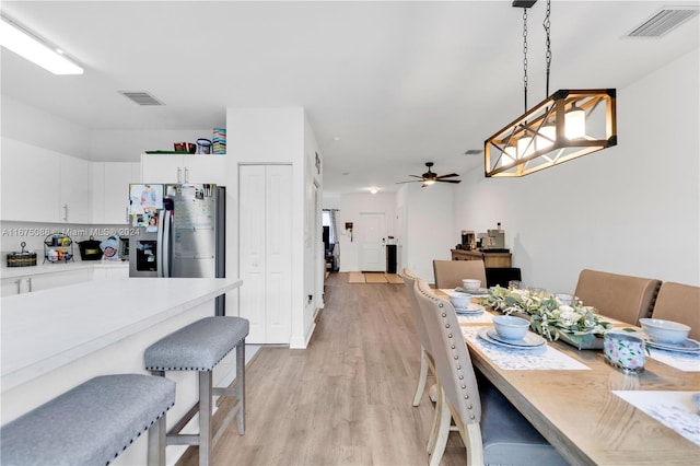 dining area with light wood-type flooring and ceiling fan