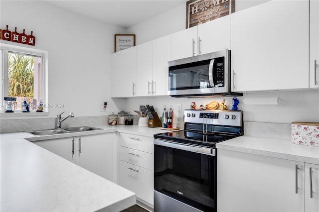 kitchen with white cabinets, hardwood / wood-style flooring, stainless steel appliances, and sink