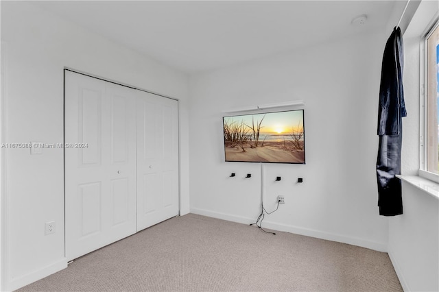 unfurnished bedroom with light colored carpet and a closet