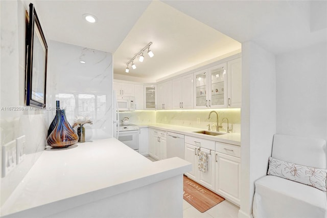 kitchen featuring tasteful backsplash, white appliances, sink, kitchen peninsula, and white cabinets