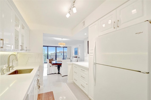 kitchen with white cabinets, light tile patterned flooring, sink, backsplash, and white fridge