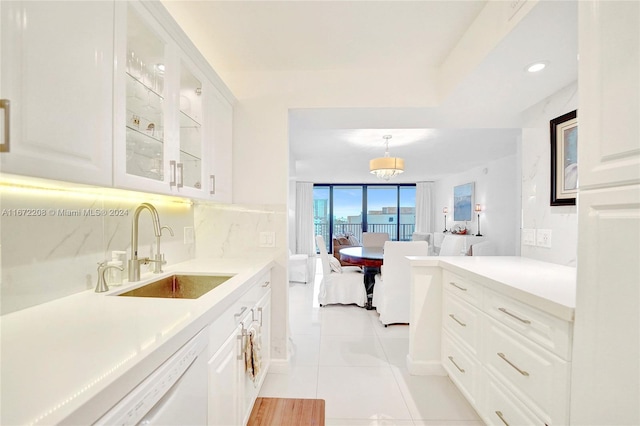 kitchen with decorative backsplash, sink, hanging light fixtures, white cabinetry, and white dishwasher