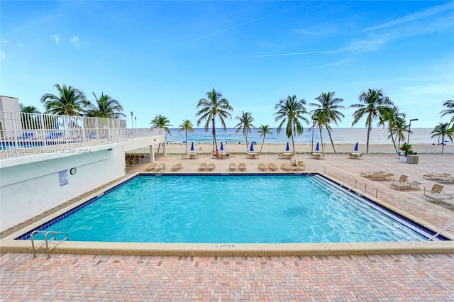 view of swimming pool featuring a water view and a patio area