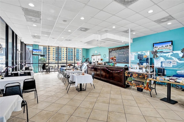 dining space with a wall of windows, a paneled ceiling, and light tile patterned floors