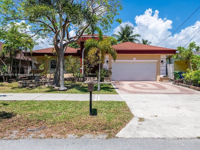232 SW 7th Ave, Hallandale Beach, FL 33009 - view of front of home featuring a garage, stucco siding, driveway, and a front yard