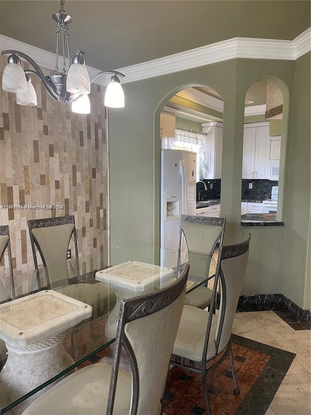 dining area with an inviting chandelier, crown molding, and sink